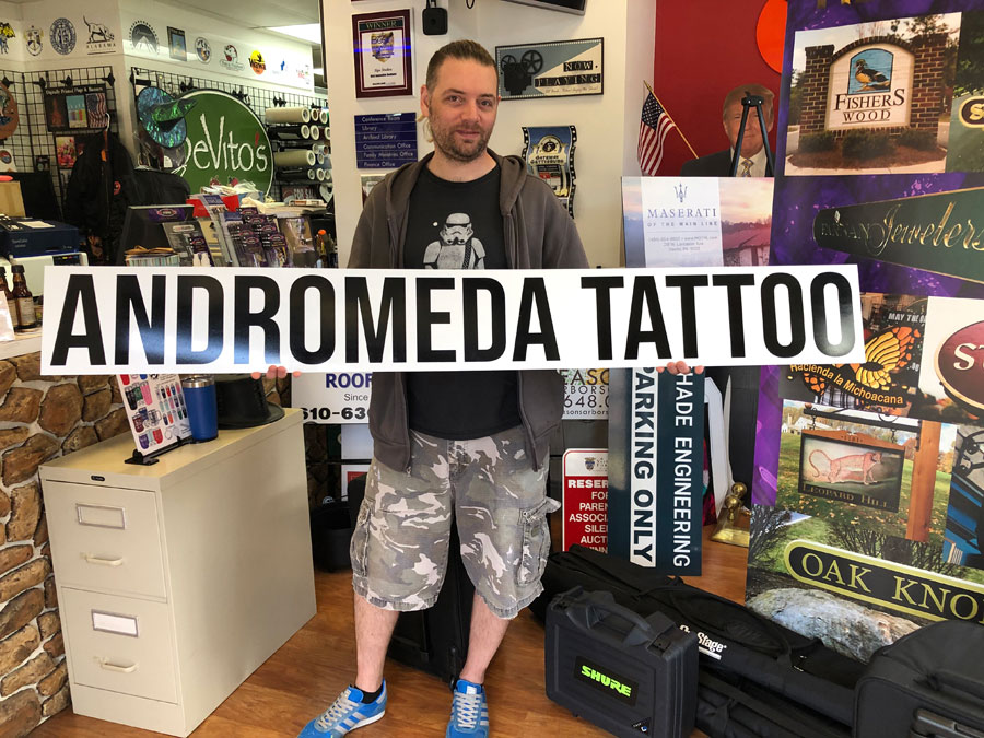 Andromeda Tattoo Sign Held by Customer